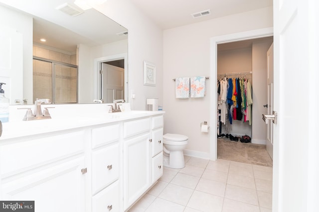 bathroom with tile patterned floors, toilet, a shower with door, and vanity