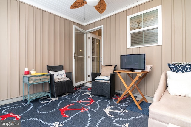 sitting room featuring wood walls and ceiling fan