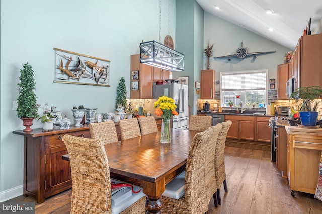 dining area featuring sink, high vaulted ceiling, and hardwood / wood-style flooring