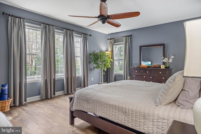 bedroom featuring multiple windows, ceiling fan, and light hardwood / wood-style flooring