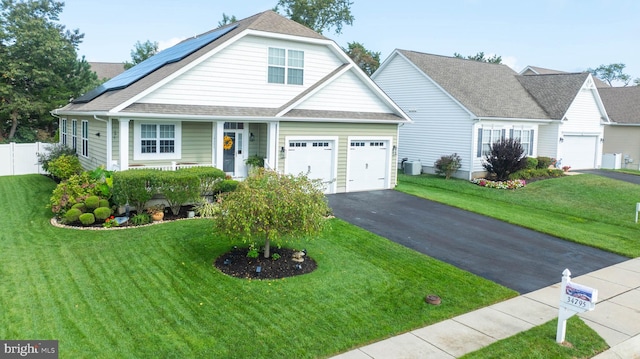 view of front of property with a front yard, solar panels, and a garage