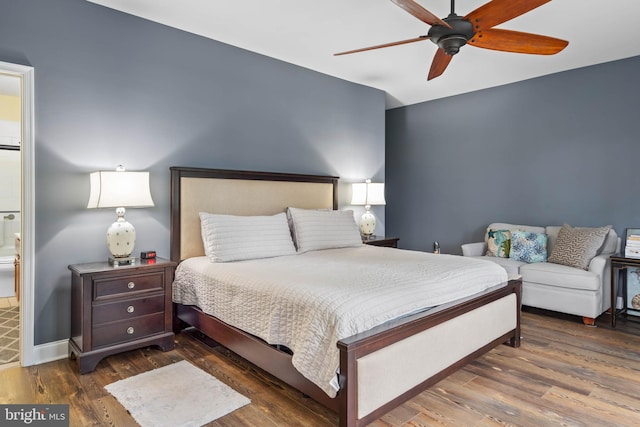 bedroom with ceiling fan, dark wood-type flooring, and ensuite bath