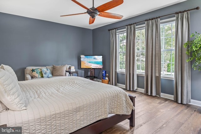 bedroom with ceiling fan, wood-type flooring, and multiple windows