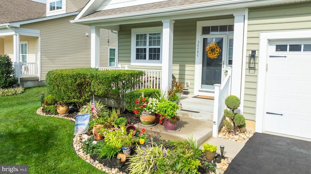 doorway to property featuring covered porch, a yard, and a garage