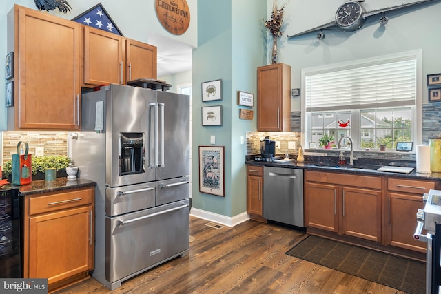 kitchen featuring decorative backsplash, stainless steel appliances, sink, dark stone countertops, and dark hardwood / wood-style floors