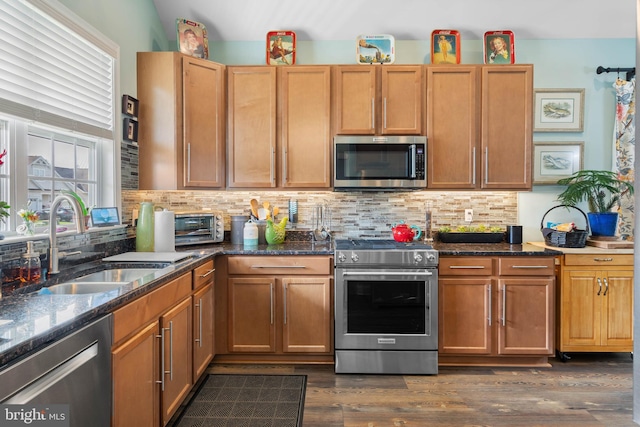 kitchen with dark hardwood / wood-style floors, sink, appliances with stainless steel finishes, and dark stone counters