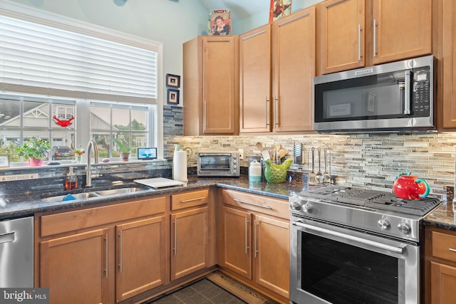 kitchen with decorative backsplash, sink, dark stone counters, and appliances with stainless steel finishes