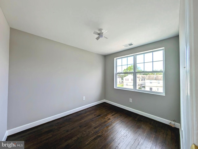 empty room featuring baseboards, visible vents, ceiling fan, and dark wood-style flooring