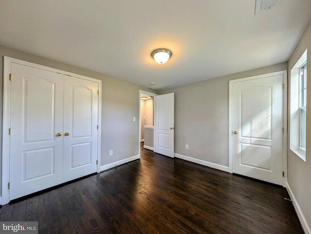 unfurnished bedroom featuring a closet, dark hardwood / wood-style flooring, and multiple windows