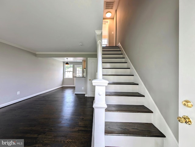 stairs with wood finished floors, ornamental molding, baseboards, and visible vents