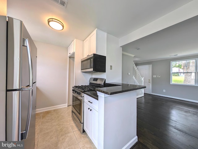 kitchen with visible vents, baseboards, stainless steel appliances, dark stone counters, and white cabinetry