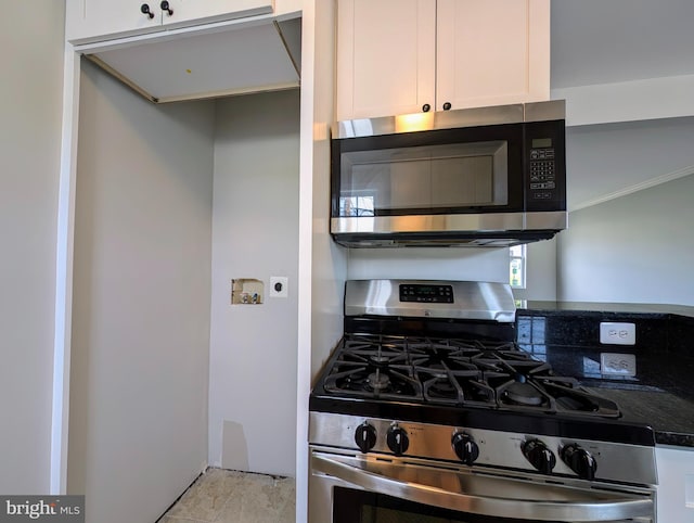 kitchen featuring dark stone counters, stainless steel appliances, and white cabinets