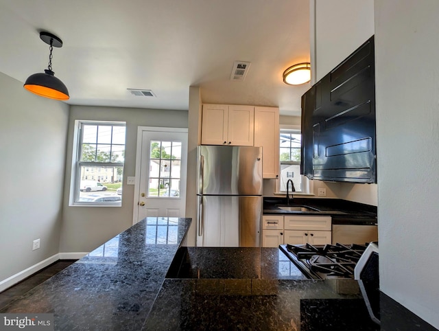 kitchen with appliances with stainless steel finishes, hanging light fixtures, sink, and white cabinets