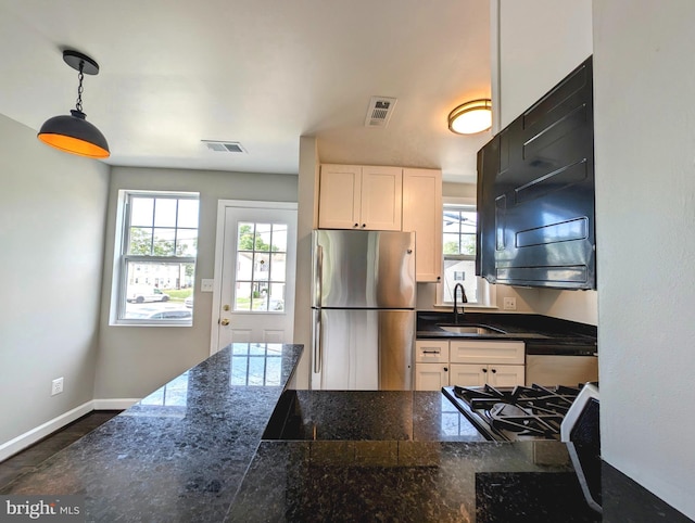 kitchen featuring a wealth of natural light, visible vents, a sink, and freestanding refrigerator