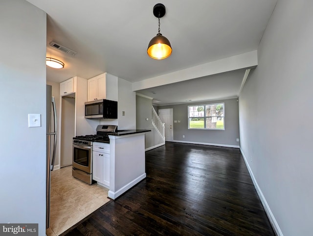 kitchen with white cabinetry, appliances with stainless steel finishes, hardwood / wood-style flooring, and hanging light fixtures