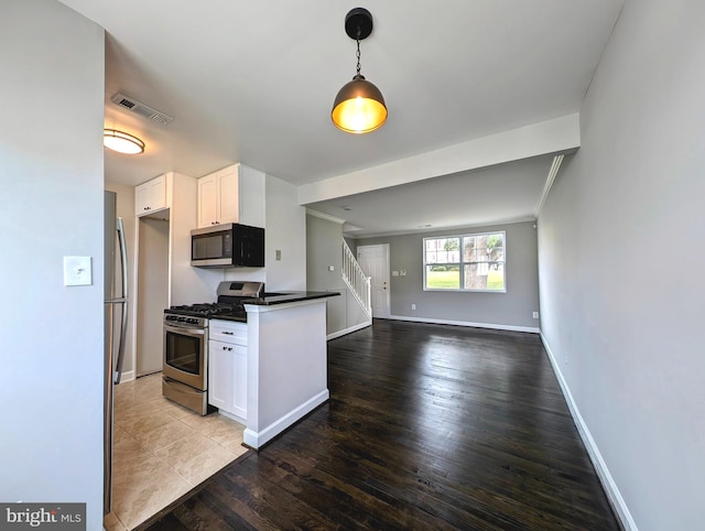 kitchen featuring appliances with stainless steel finishes, dark countertops, baseboards, visible vents, and white cabinets