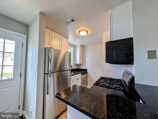 kitchen featuring dark stone counters, kitchen peninsula, stainless steel appliances, and white cabinets