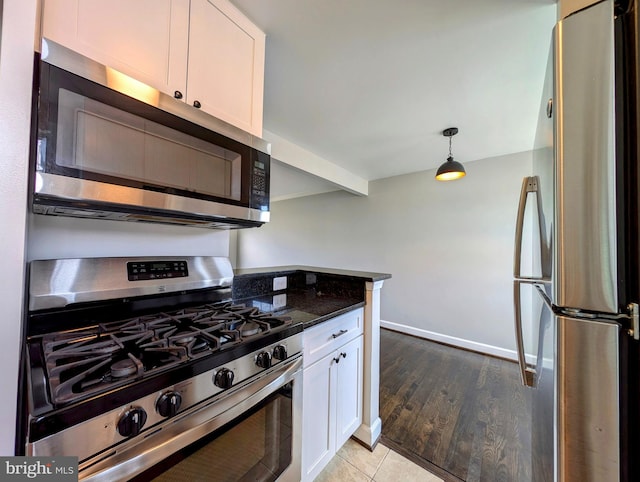 kitchen featuring white cabinetry, light hardwood / wood-style floors, appliances with stainless steel finishes, and decorative light fixtures