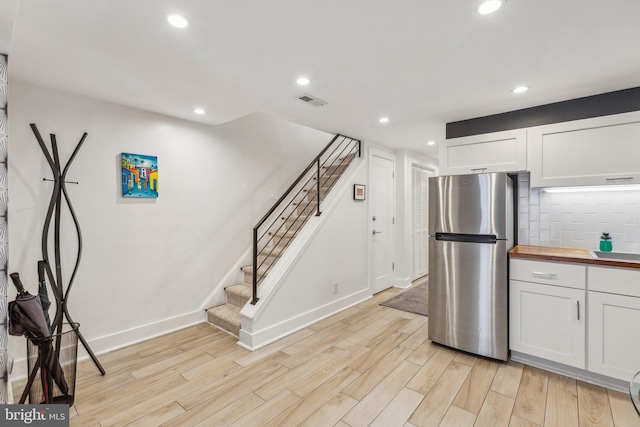 kitchen featuring light hardwood / wood-style flooring, stainless steel fridge, and white cabinetry