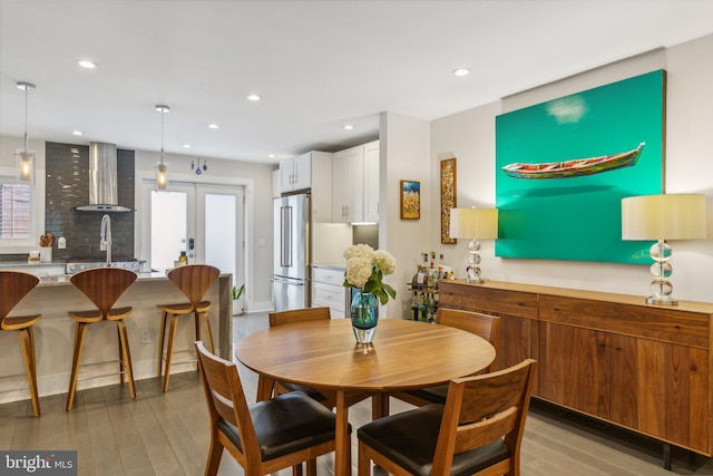 dining room with french doors, light wood-type flooring, and sink