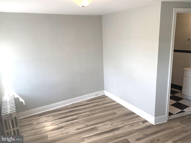 empty room featuring radiator and hardwood / wood-style floors