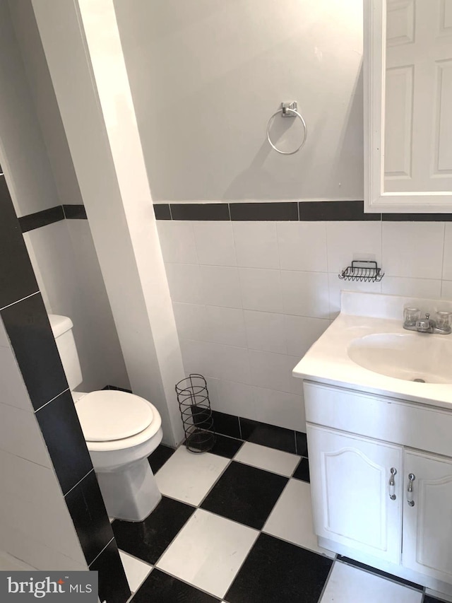 bathroom featuring tile walls, vanity, and toilet