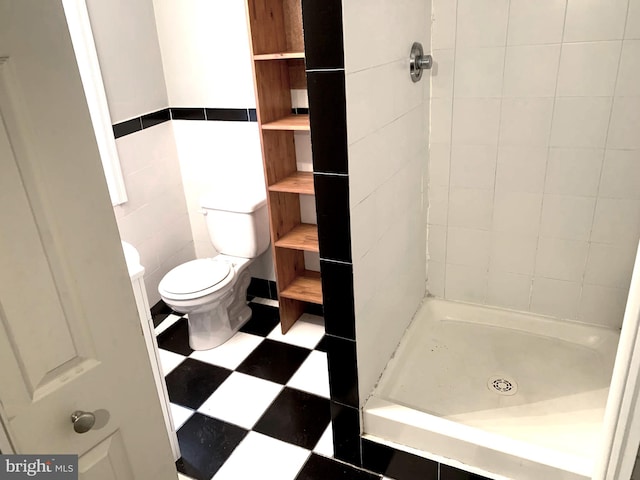 bathroom featuring a tile shower, tile walls, and toilet