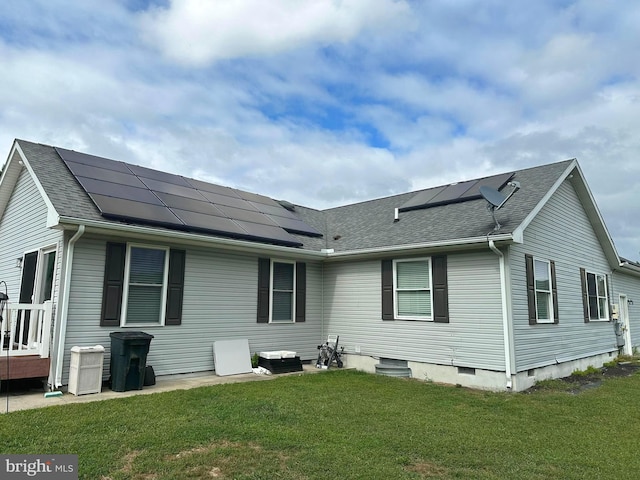 back of property featuring solar panels and a yard