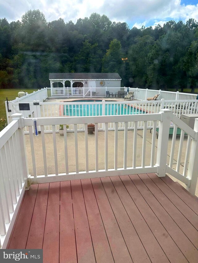 wooden terrace featuring a fenced in pool and a patio area