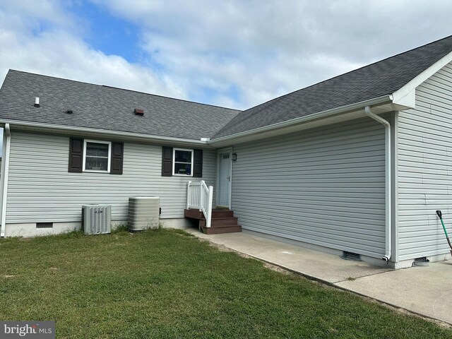 rear view of house featuring cooling unit and a yard