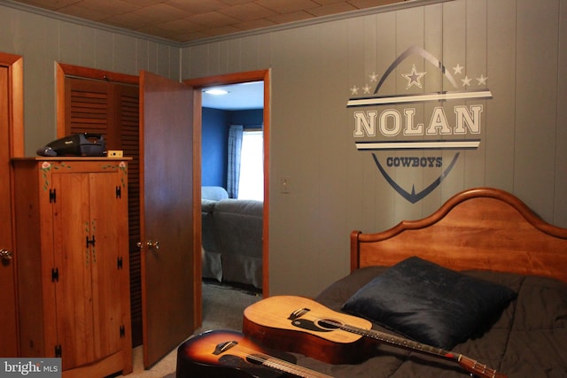 carpeted bedroom featuring wooden walls