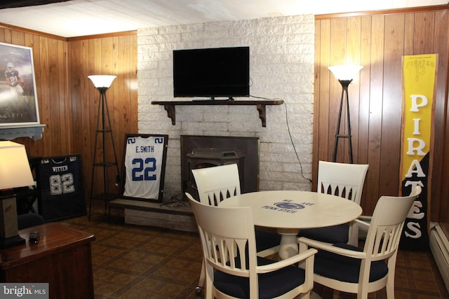 dining area featuring a fireplace, wood walls, and a baseboard radiator