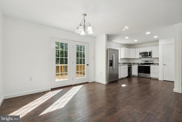 kitchen featuring dark wood-type flooring, stainless steel appliances, a notable chandelier, pendant lighting, and white cabinets