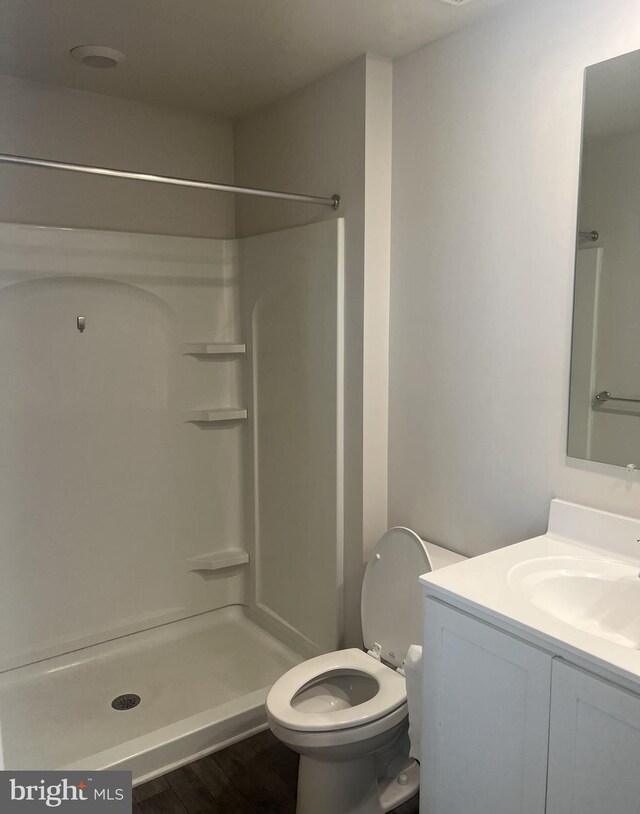 bathroom with a shower, vanity, toilet, and hardwood / wood-style flooring