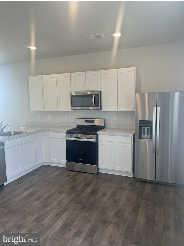 kitchen with white cabinets, sink, appliances with stainless steel finishes, light stone countertops, and dark hardwood / wood-style flooring