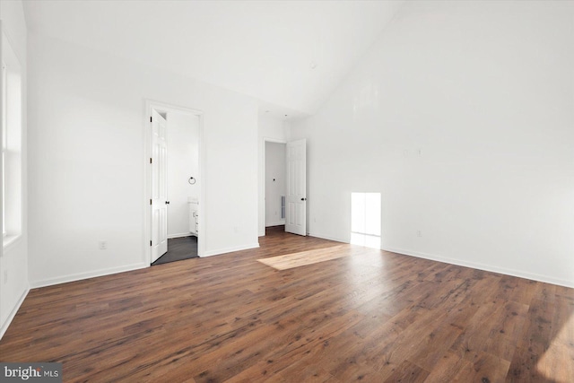 unfurnished bedroom with dark hardwood / wood-style floors, high vaulted ceiling, and connected bathroom