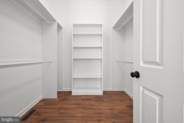 walk in closet with dark hardwood / wood-style floors