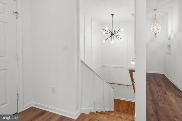 stairs with hardwood / wood-style floors and a chandelier