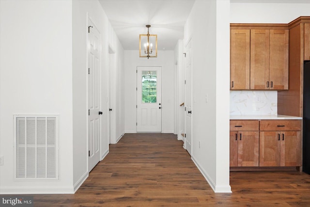 hall with an inviting chandelier and dark wood-type flooring