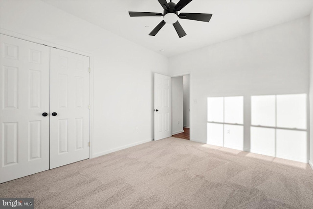 unfurnished bedroom featuring ceiling fan, light colored carpet, and a closet