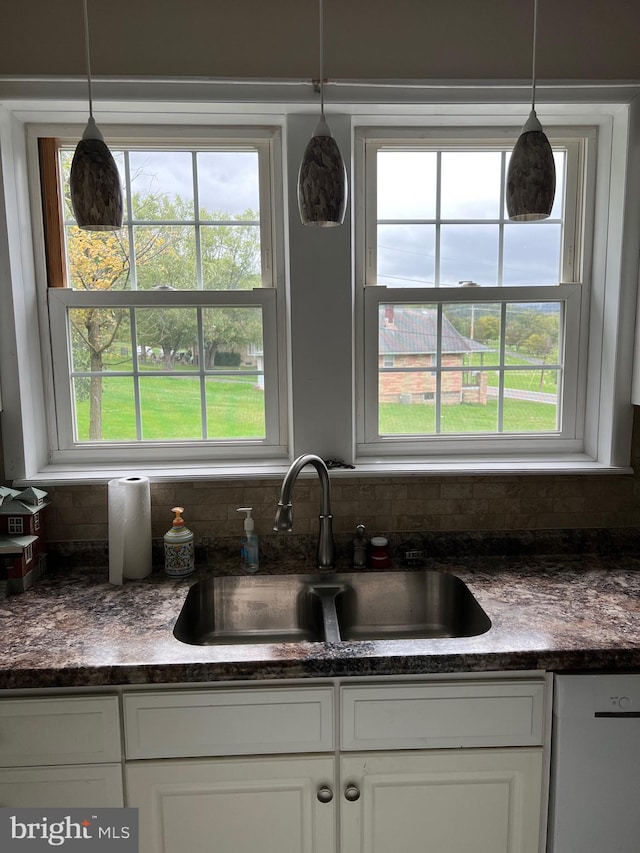 kitchen featuring dishwasher, decorative light fixtures, sink, and white cabinetry