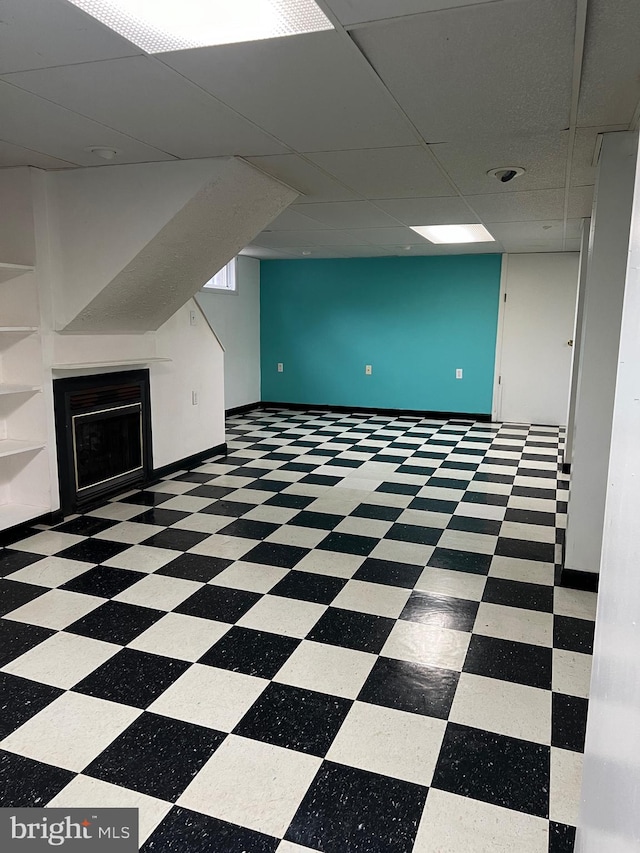 basement featuring built in shelves and a drop ceiling