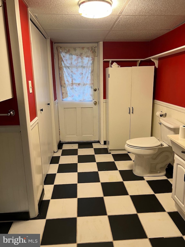 bathroom featuring vanity, a drop ceiling, and toilet