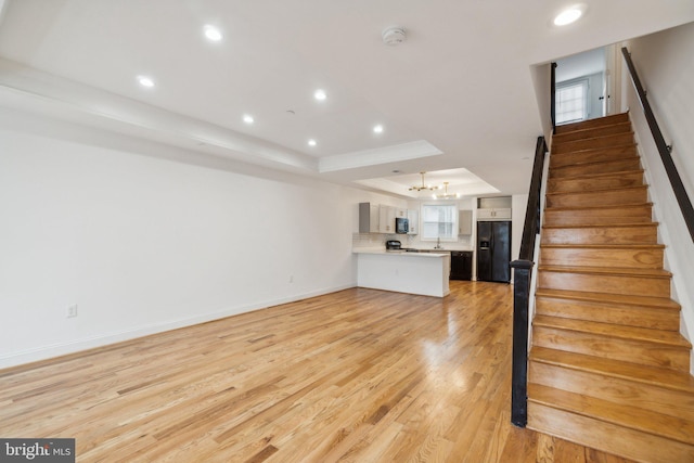 interior space featuring wood-type flooring, a chandelier, and a raised ceiling