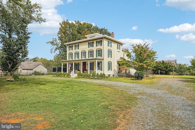 view of front of house featuring a chimney, a front lawn, fence, and gravel driveway