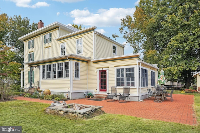 rear view of house with a yard, a patio, entry steps, and a chimney