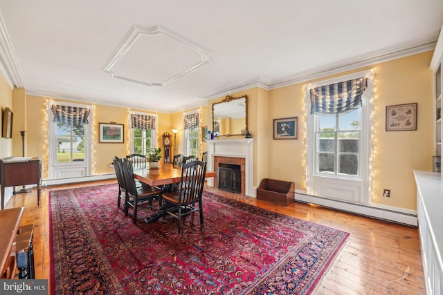 dining room with baseboard heating, a baseboard radiator, hardwood / wood-style floors, and plenty of natural light