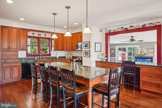 kitchen with a sink, stainless steel microwave, black dishwasher, and dark wood finished floors