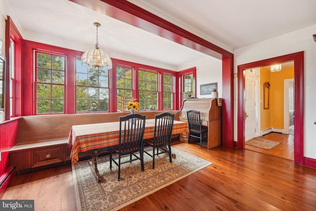 dining space featuring an inviting chandelier, breakfast area, baseboard heating, hardwood / wood-style floors, and baseboards