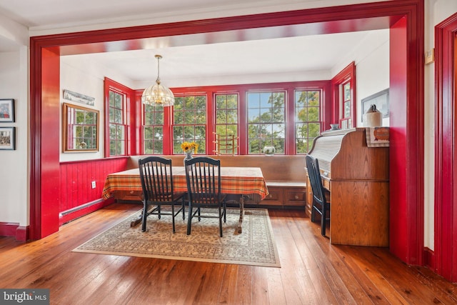 dining space with an inviting chandelier, hardwood / wood-style flooring, wainscoting, breakfast area, and a baseboard heating unit